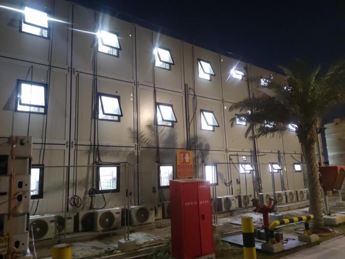 Accommodation building facade at night with lit windows and wall-mounted units