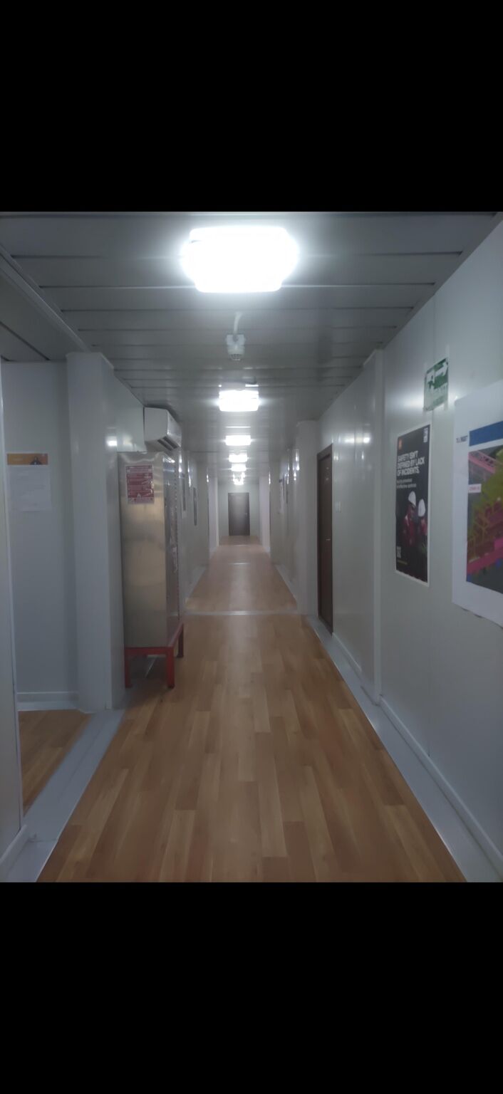 Internal accommodation corridor with lit ceiling and room doors on both sides