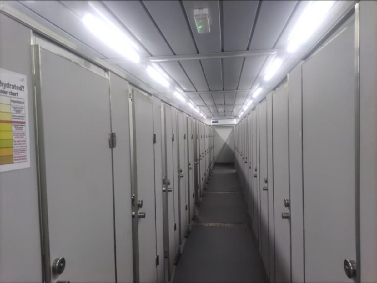 Long corridor lined with shower and toilet cubicle doors