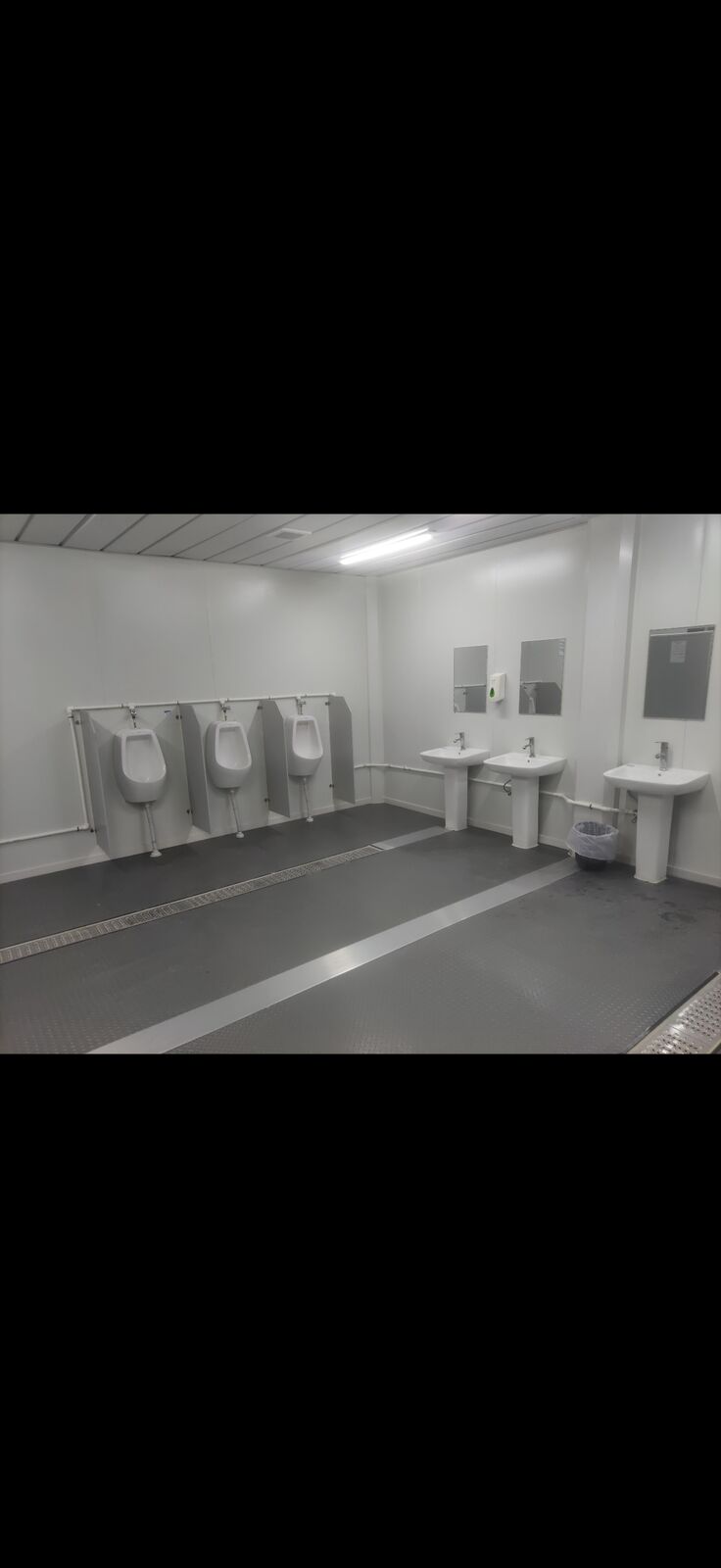 Sanitary facility with urinals, washbasins and tiled floor